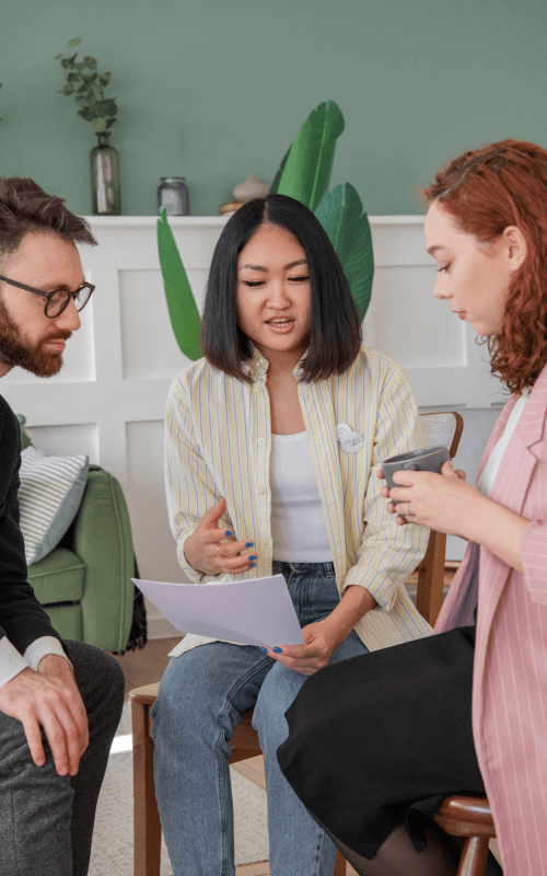 three people discussing documents indoors