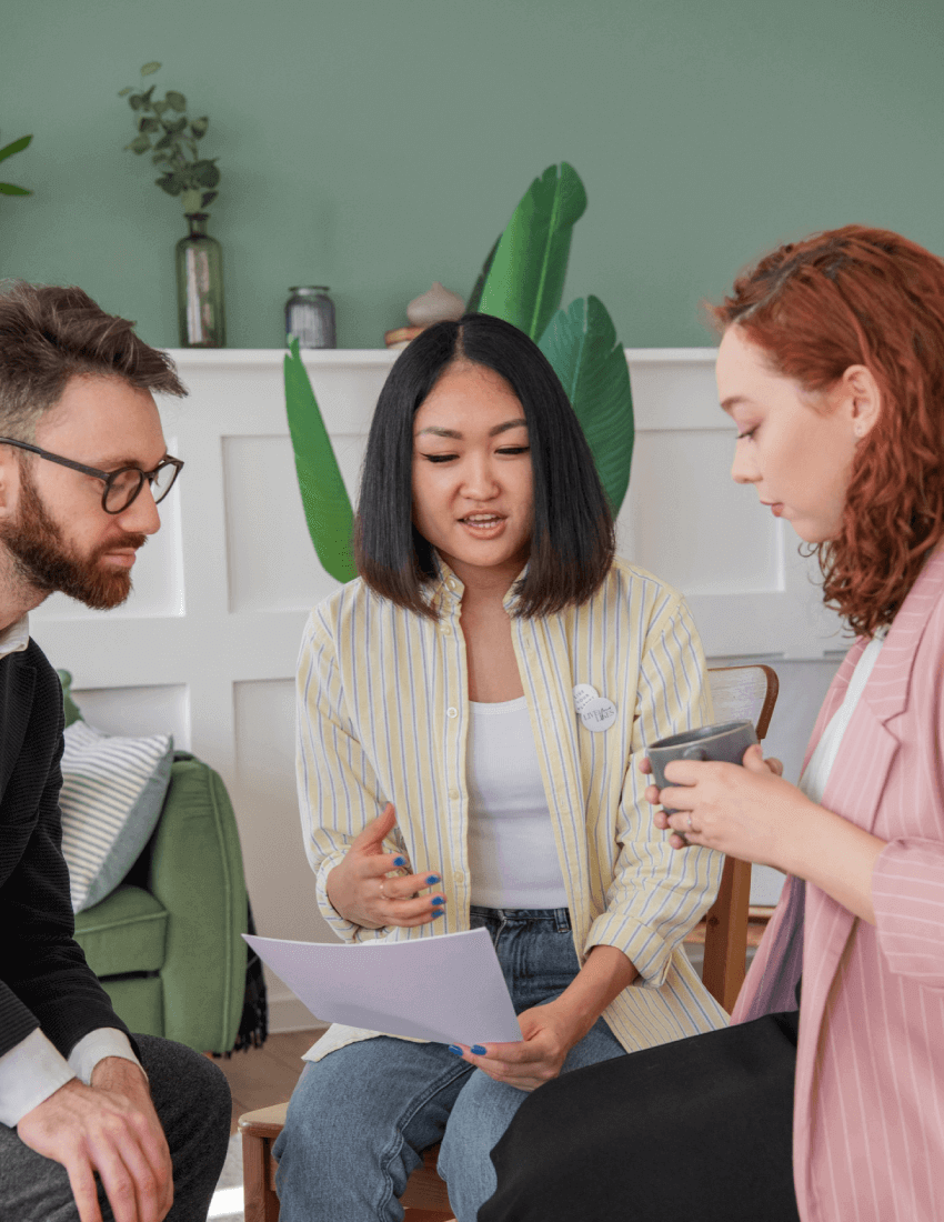 Three people discussing documents indoors