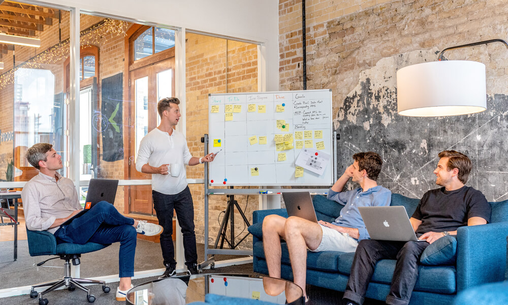 team brainstorming at whiteboard, laptops open