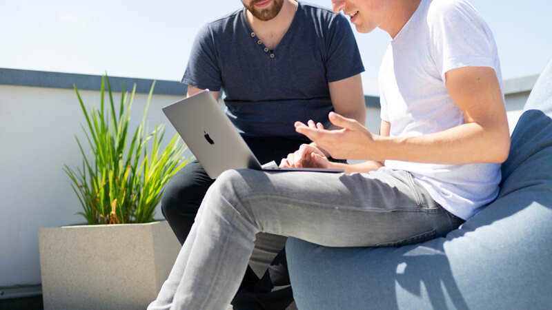 two men working outdoors on laptop